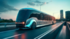 A modern, autonomous electric bus with a reflective surface driving on a city highway at dusk, with urban high-rise buildings in the background and a warm sunset on the horizon, representing the future of public transportation.
