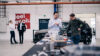 Automotive engineers examining EV components at a modern workspace with electric car in background, showcasing innovation and technology collaboration.
