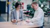Two professionals reviewing technical components and engineering documentation at a collaborative workspace within a modern industrial environment.