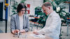 Two professionals reviewing technical components and engineering documentation at a collaborative workspace within a modern industrial environment.