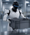 Humanoid robot holding a plastic container in an industrial facility