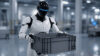 Humanoid robot holding a plastic container in an industrial facility