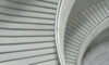 Curved concrete staircase with metal handrails viewed from above.