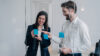 Two business professionals collaborating with sticky notes on a glass wall in a modern office.