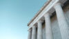Classical building facade with large stone columns against a clear blue sky.