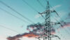 High-voltage transmission tower and power lines against a blue evening sky.