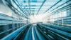 High speed rail tracks curving through a modern covered railway infrastructure with strong motion blur.