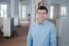 Professional portrait of an employee standing in a modern office environment.