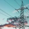 High-voltage transmission tower and power lines against a blue evening sky.