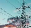 High-voltage transmission tower and power lines against a blue evening sky.