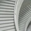 Curved concrete staircase with metal handrails viewed from above.
