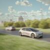 Electric passenger vehicle powered by a solid-state battery driving past wind turbines.