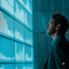 Business professional analyzing data visualizations and performance metrics on a large digital dashboard, supporting data-driven decision-making and strategic planning.