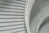 Curved concrete staircase with metal handrails viewed from above.